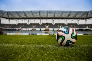 A football on the pitch under stadium lights